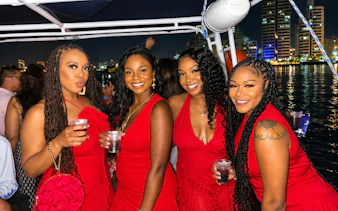 Group enjoying drinks on a sunset party cruise in Cartagena with city skyline in the background.