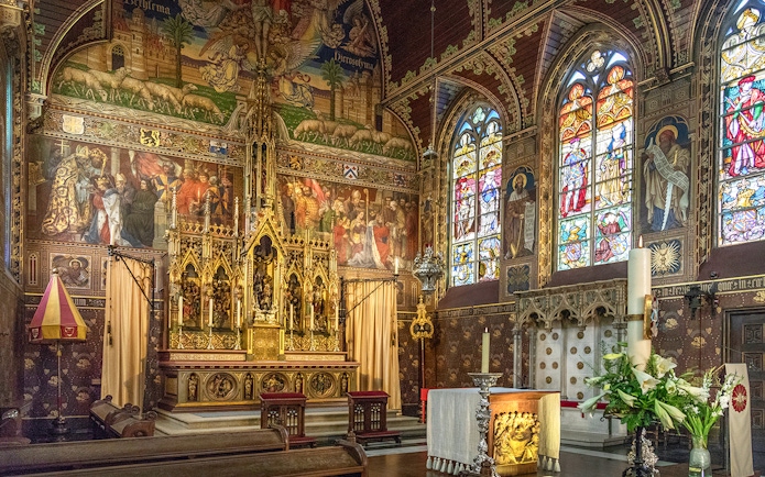 Bruges Basilica of the Holy Blood interior with ornate altar and stained glass windows.