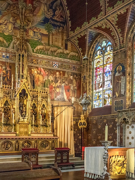 Bruges Basilica of the Holy Blood interior with ornate altar and stained glass windows.