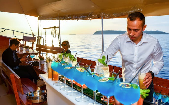 Mixologist serving blue cocktails on a boat with ocean view.