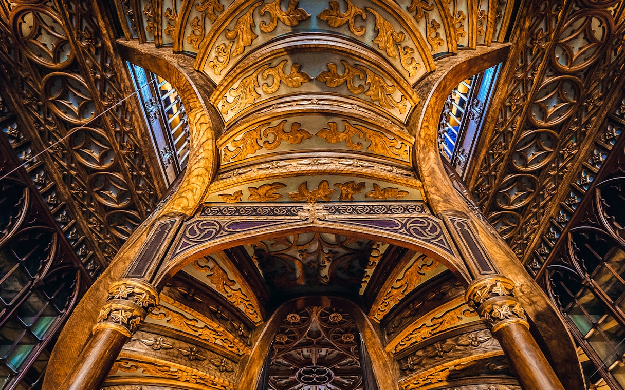 Ornate wooden ceiling and staircase inside Lello Bookstore, Porto, Portugal.