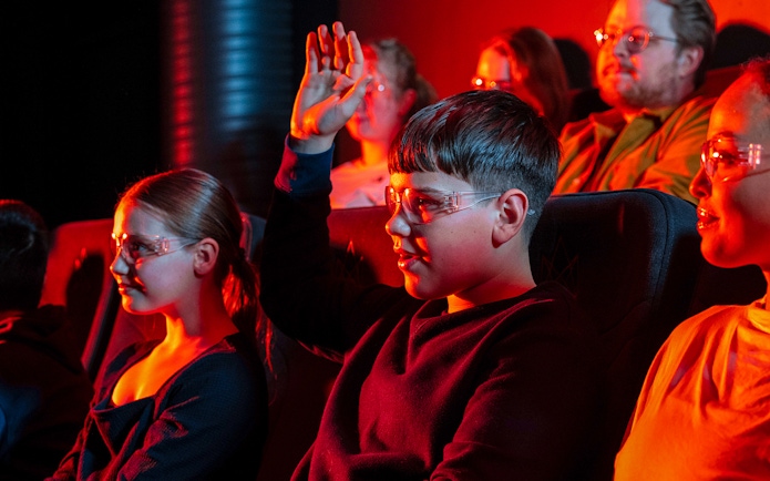 Guests watching the Lava show in Reykjavik, wearing protective glasses.