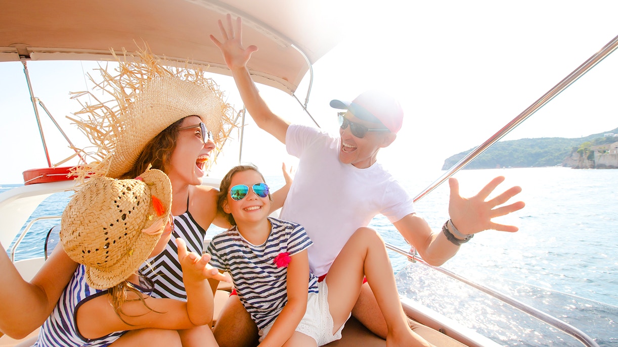Family enjoying a speedboat ride on the ocean near a coastal landscape.