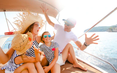 Family enjoying a speedboat ride on the ocean near a coastal landscape.