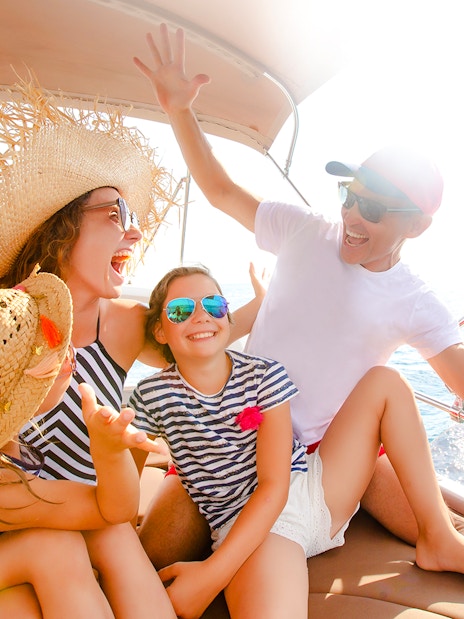 Family enjoying a speedboat ride on the ocean near a coastal landscape.