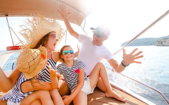 Family enjoying a speedboat ride on the ocean near a coastal landscape.