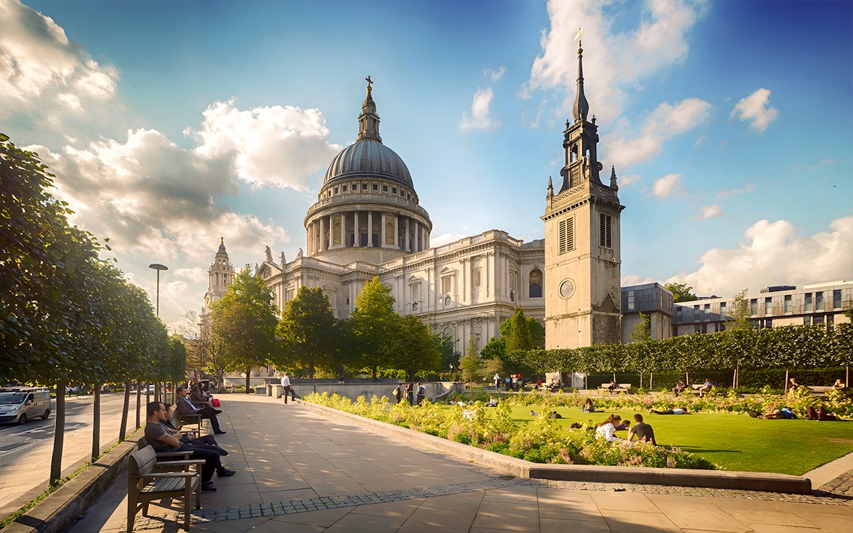 St. Paul's Cathedral in London with people relaxing in the garden.