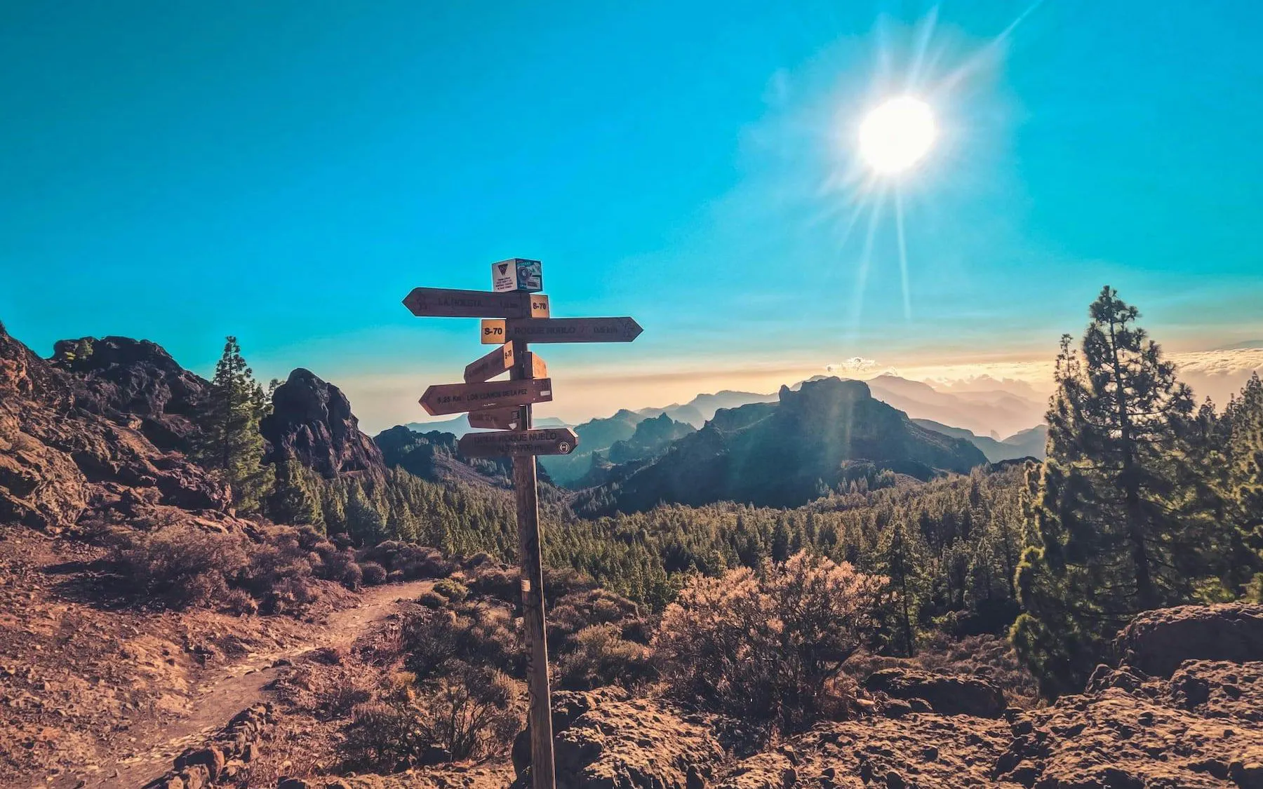Trail signpost on volcanic landscape at sunset, Gran Canaria.