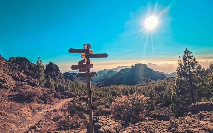 Trail signpost on volcanic landscape at sunset, Gran Canaria.