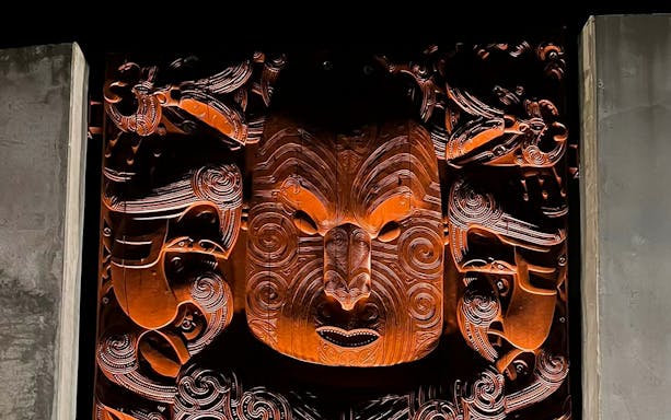 Maori carving illuminated at night during Te Puia Geysers private guided tour.