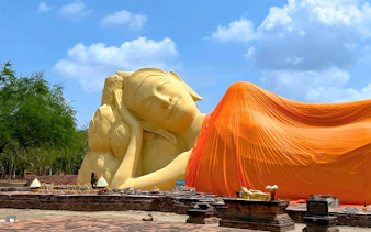 Reclining Buddha statue draped in orange cloth at Ayutthaya Temples, Thailand.