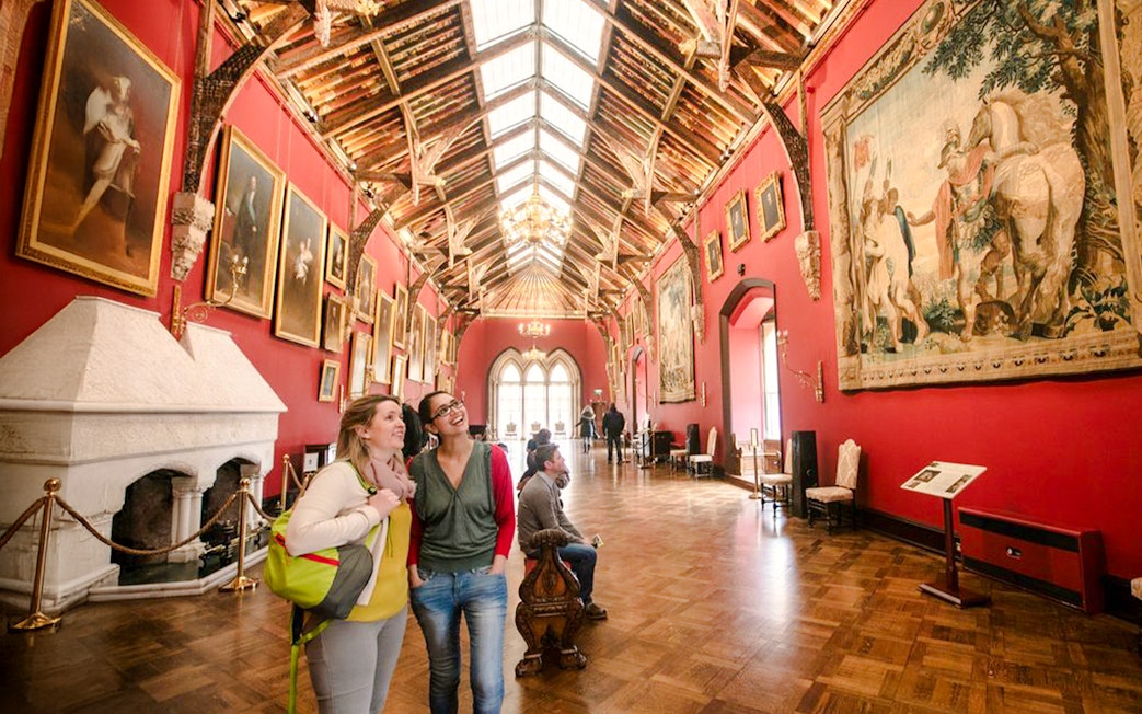 Visitors exploring the art-filled gallery of Kilkenny Castle with ornate ceiling and historic paintings.