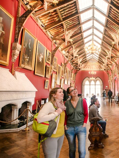 Visitors exploring the art-filled gallery of Kilkenny Castle with ornate ceiling and historic paintings.
