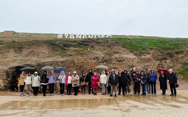 Group of tourists with umbrellas at Yanardag, Azerbaijan, near burning hillside.