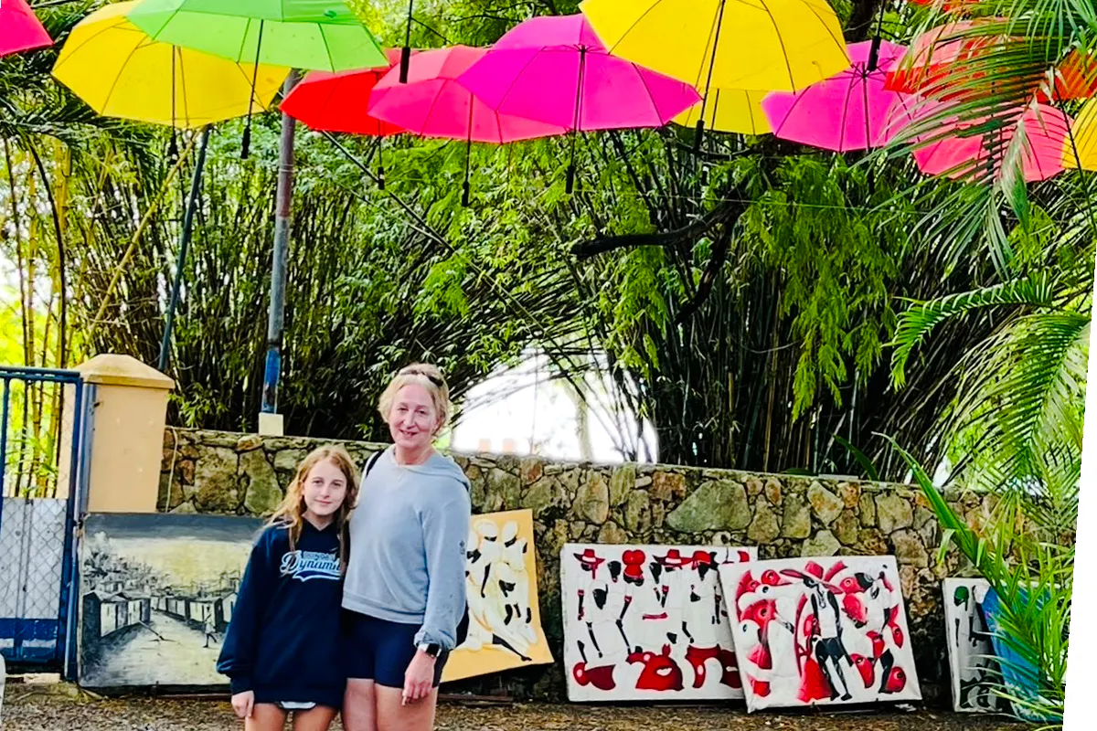 Visitors at Punta Cana artisan market with colorful umbrellas and local paintings.