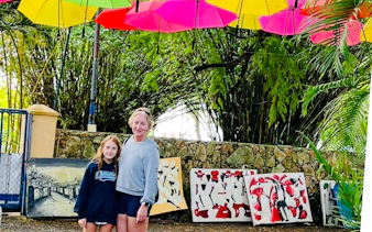 Visitors at Punta Cana artisan market with colorful umbrellas and local paintings.