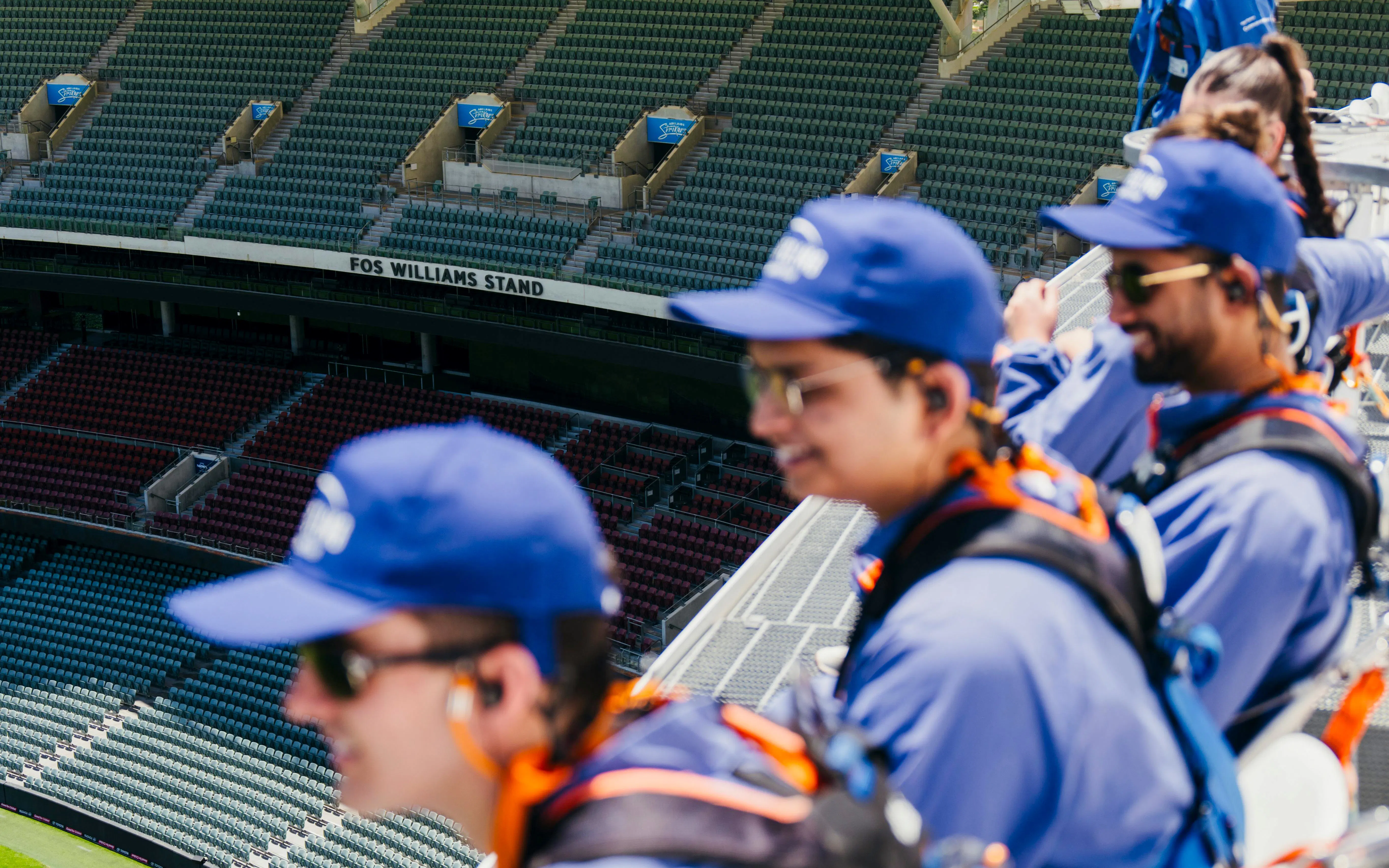 Participants on Adelaide Oval roof climb overlooking stadium seats.