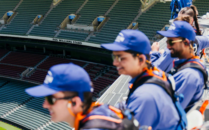Participants on Adelaide Oval roof climb overlooking stadium seats.