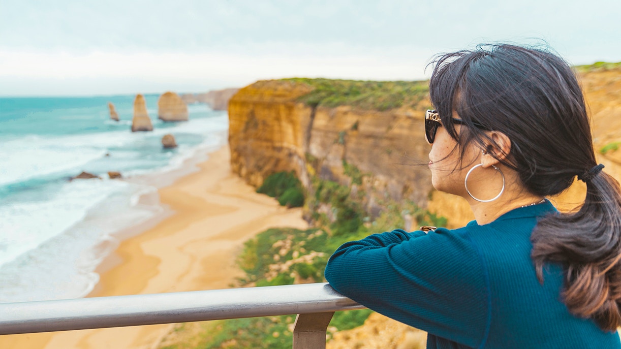 Woman at viewpoint overlooking 12 Apostles along Great Ocean Road, Melbourne.