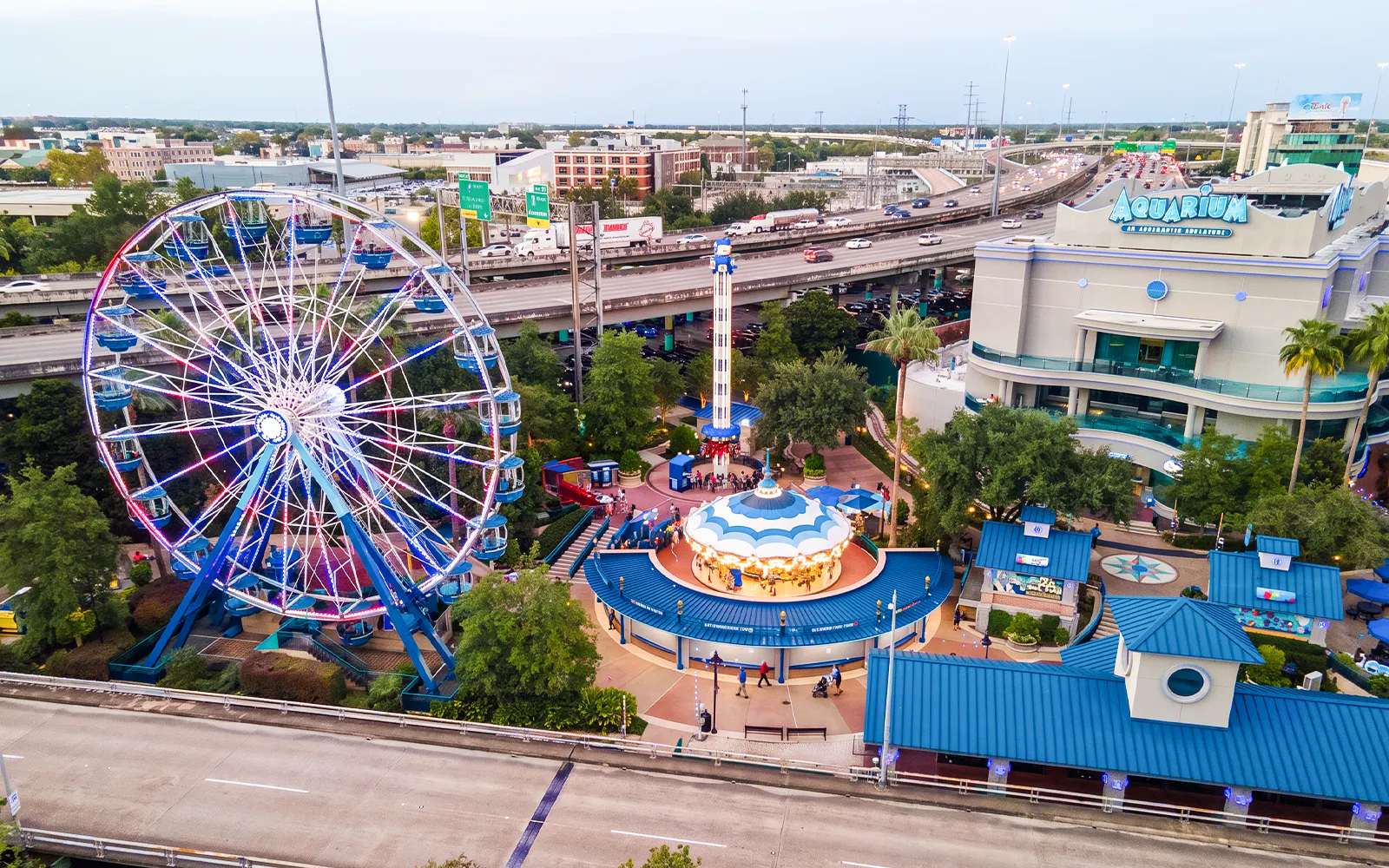 Ferris wheel and carousel at Downtown Aquarium Houston with nearby highway.