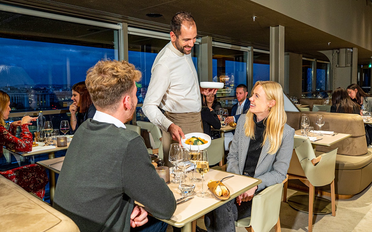 Waiter serving dinner at Madame Brasserie in the Eiffel Tower, Paris.