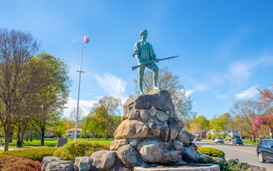 Minute Man Statue on Battle Green, Lexington, Massachusetts, with American flag in background.