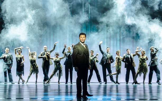 Cast performing on stage in The Great Gatsby Musical with a smoky backdrop.