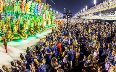 Crowd enjoying vibrant parade floats at Rio Carnival 2027, Marquês de Sapucaí, Rio de Janeiro.