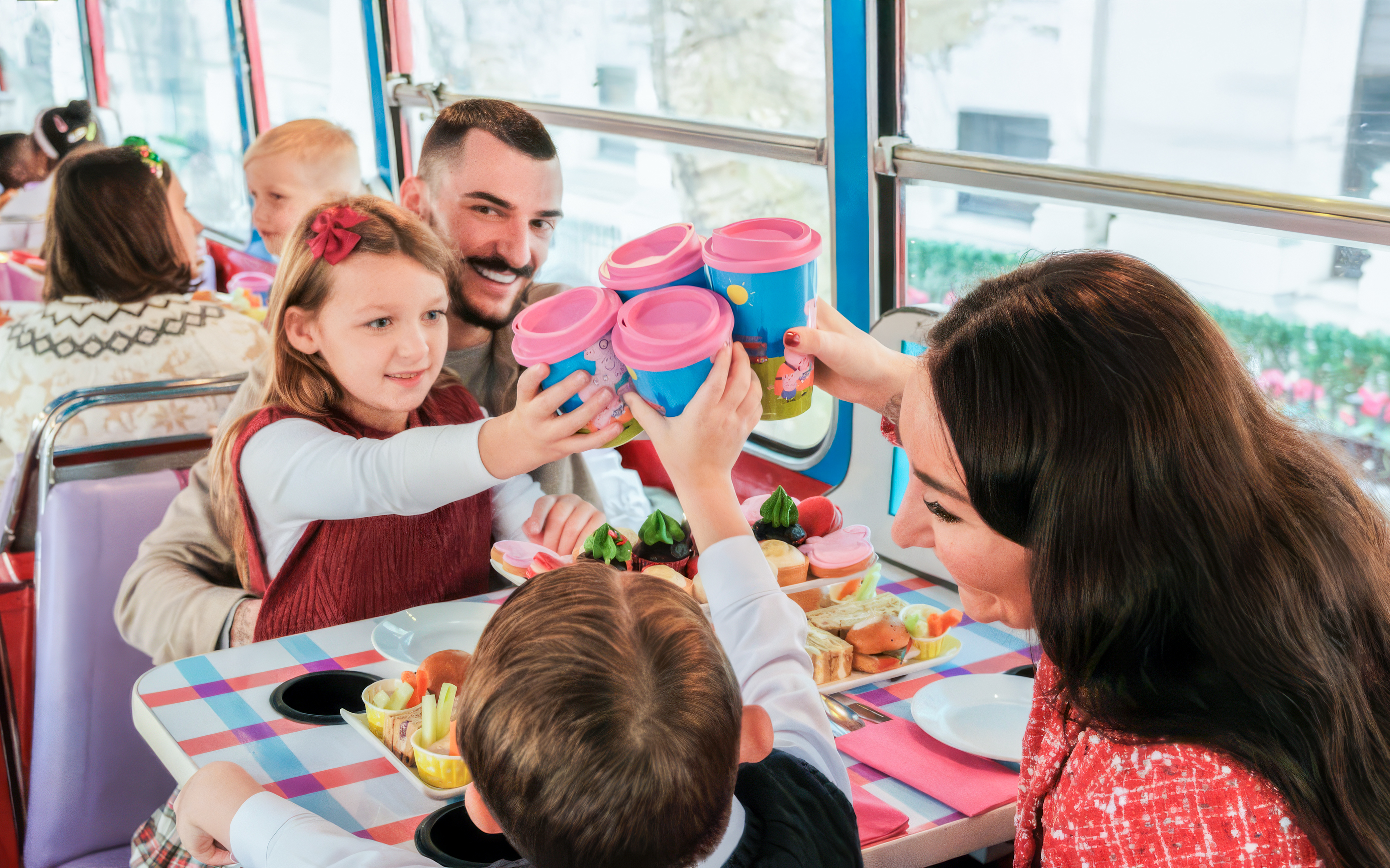 Kids and parents enjoying snacks on Peppa Pig themed bus tour.