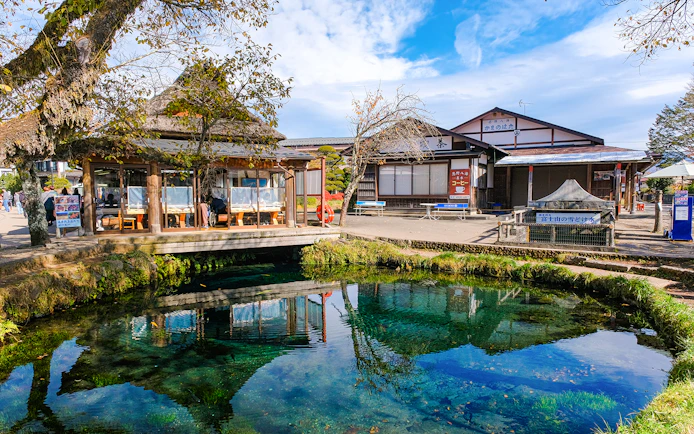 Owaike Pond in Oshino Hakkai Village, Japan, with traditional buildings and clear water.