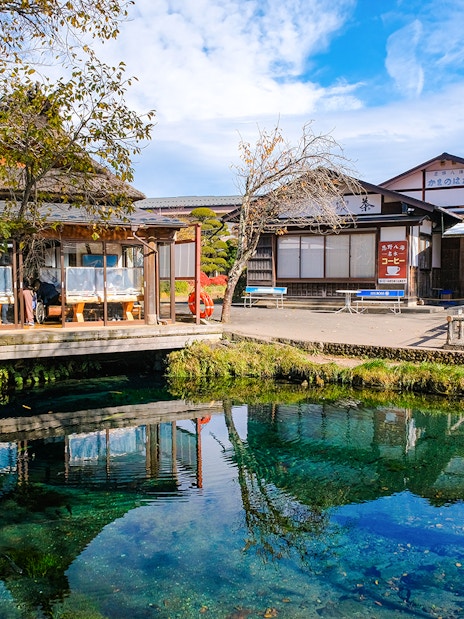 Owaike Pond in Oshino Hakkai Village, Japan, with traditional buildings and clear water.