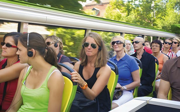 Passengers on a hop-on hop-off tour bus in Copenhagen wearing audio guides.