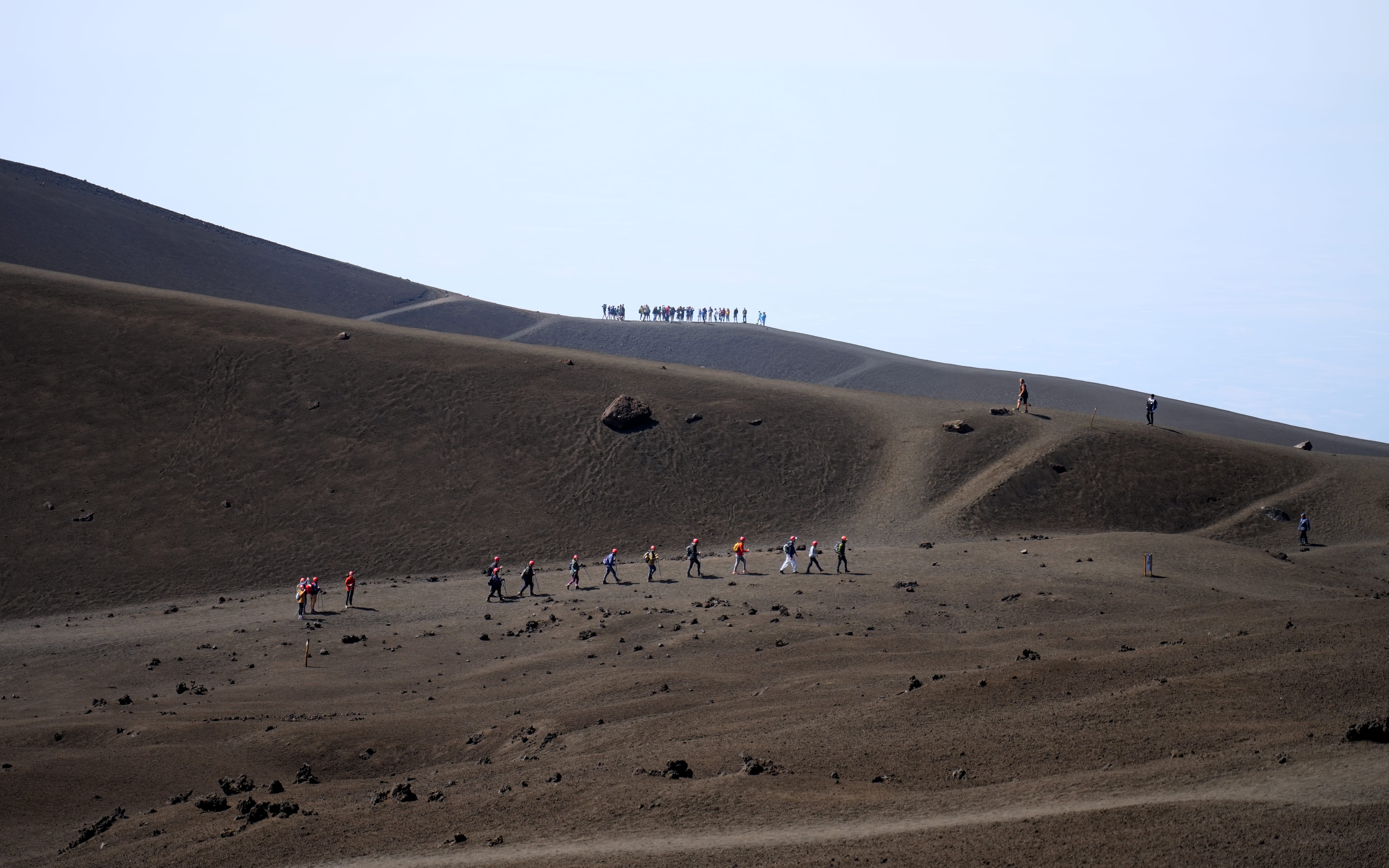 Hikers trekking on Mount Etna's volcanic landscape during a guided summit hike.