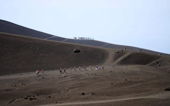 Hikers trekking on Mount Etna's volcanic landscape during a guided summit hike.
