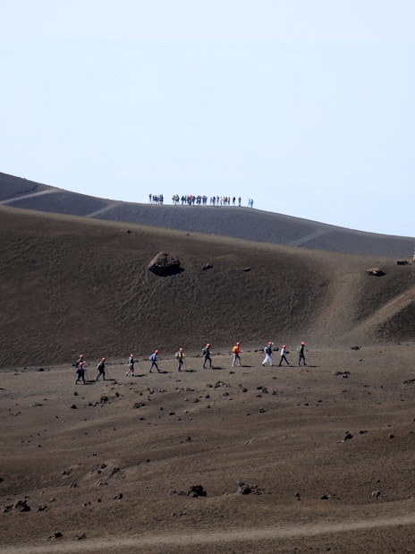 Hikers trekking on Mount Etna's volcanic landscape during a guided summit hike.