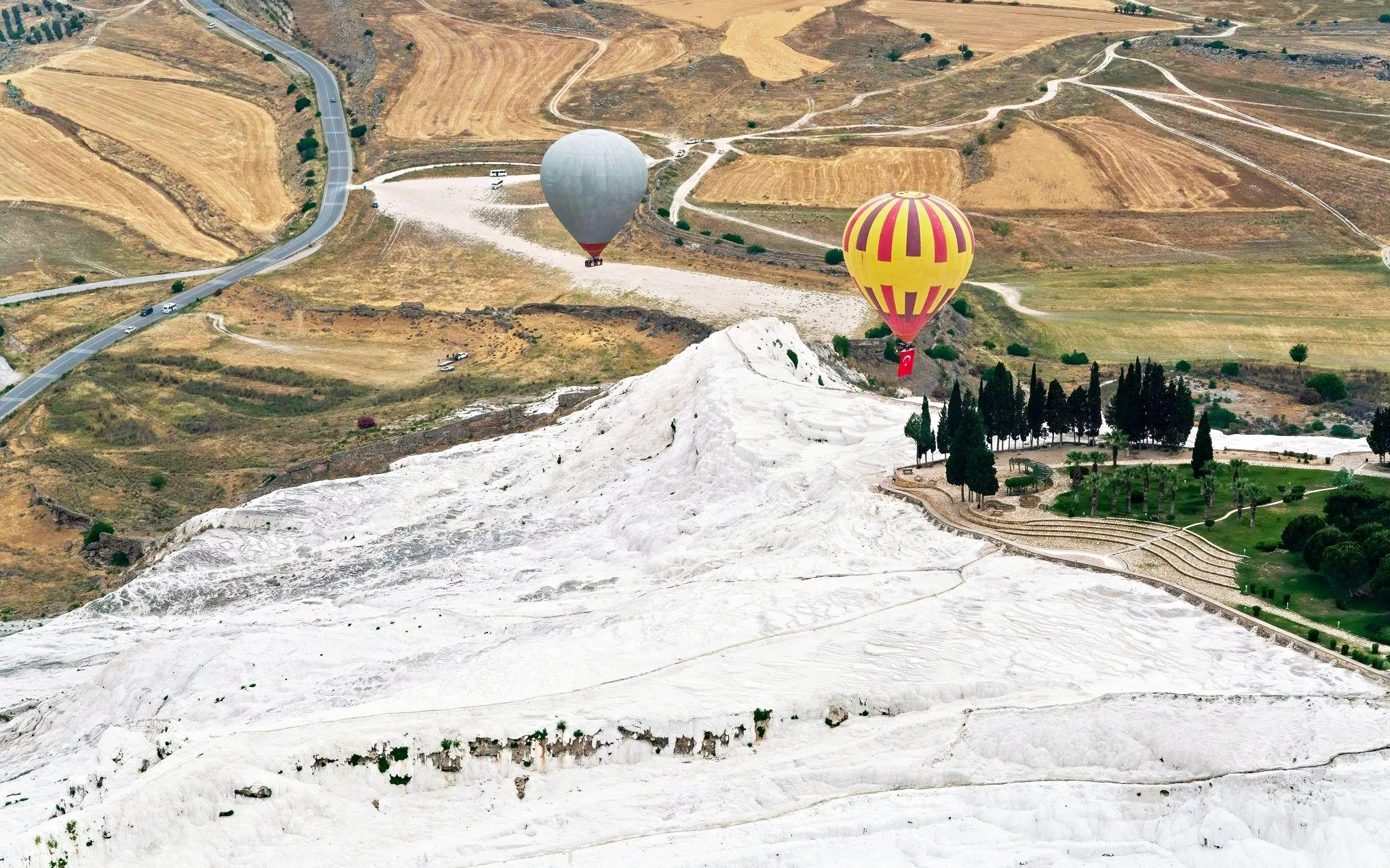 Hot air balloons over Pamukkale's travertine terraces in Turkey.