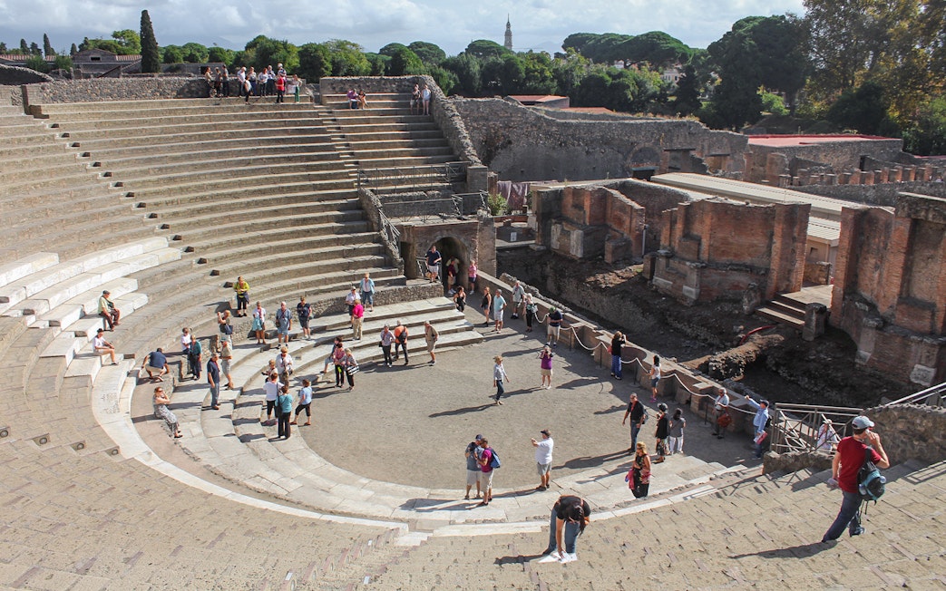 Tour group with guide at Pompeii amphitheatre, Italy.