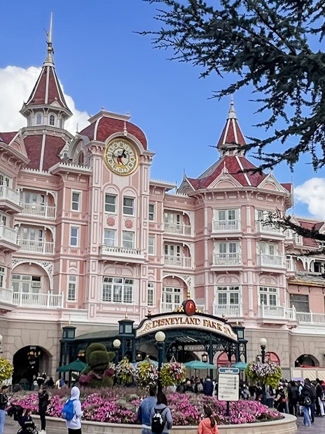 Disneyland Paris entrance with pink Victorian-style hotel and clock tower.