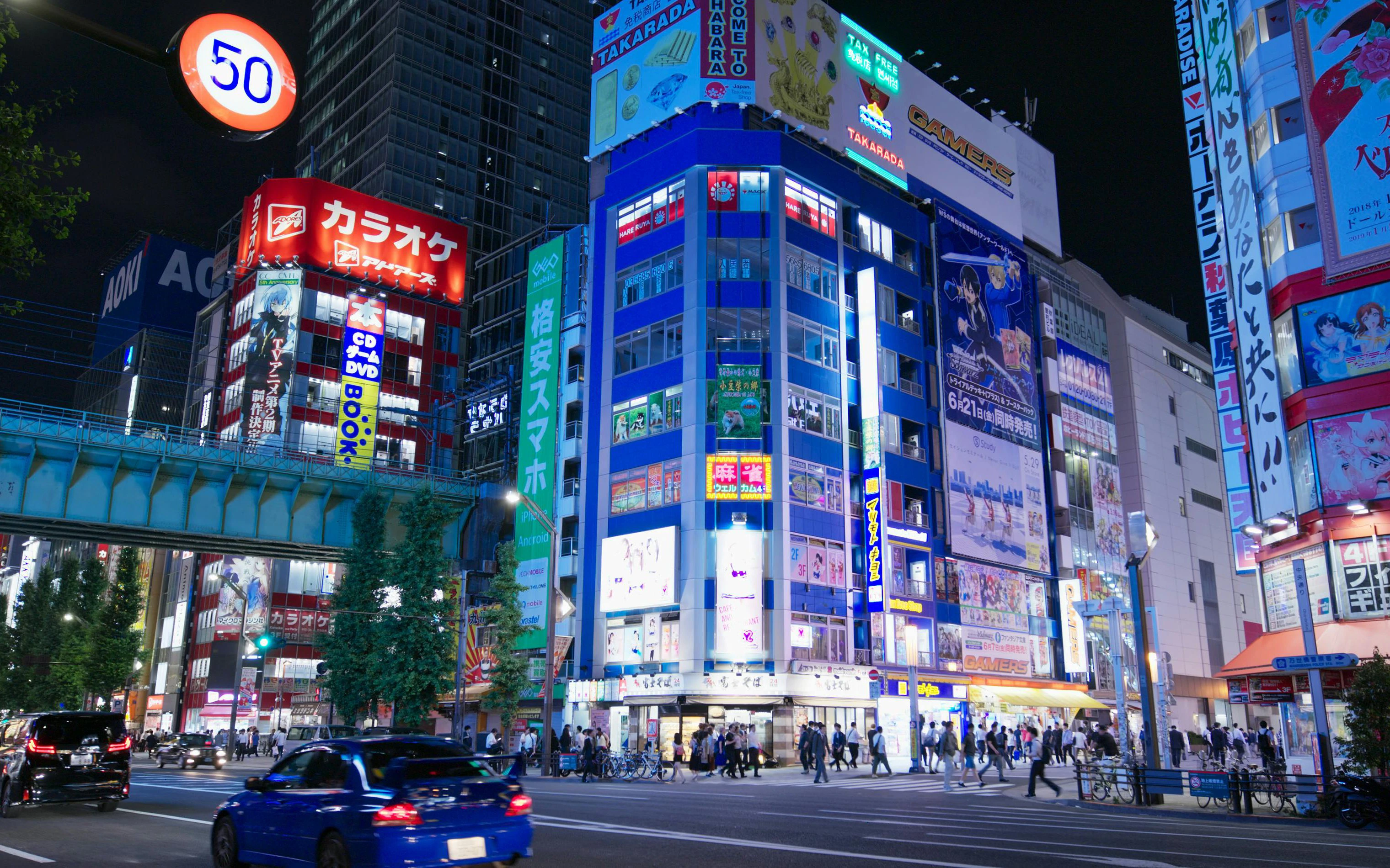 Akihabara street scene in Tokyo at night with illuminated buildings and colorful signs.