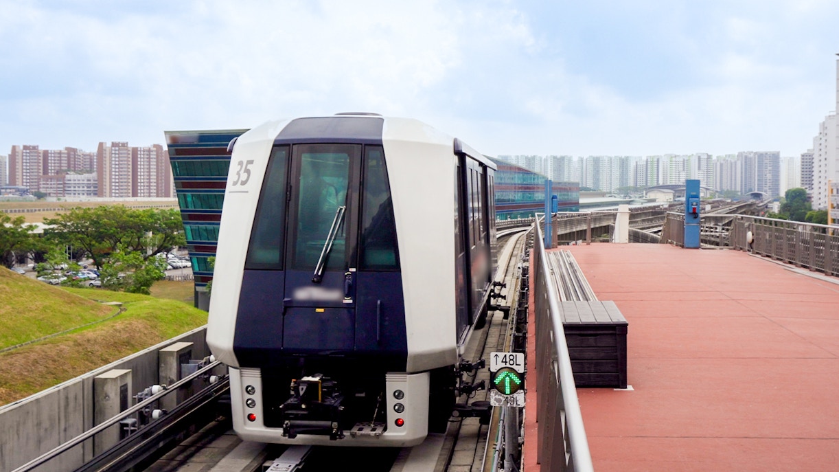 Singapore MRT train on elevated track with city skyline in the background.