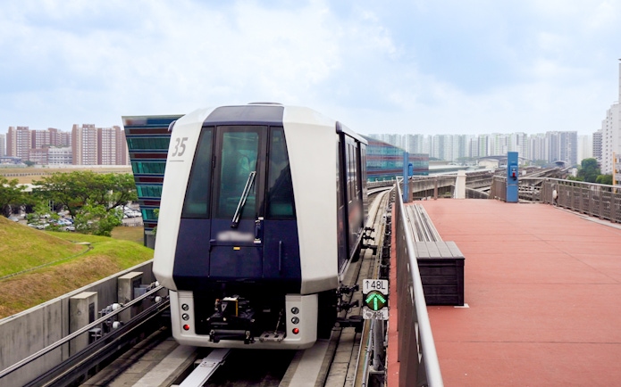Singapore MRT train on elevated track with city skyline in the background.