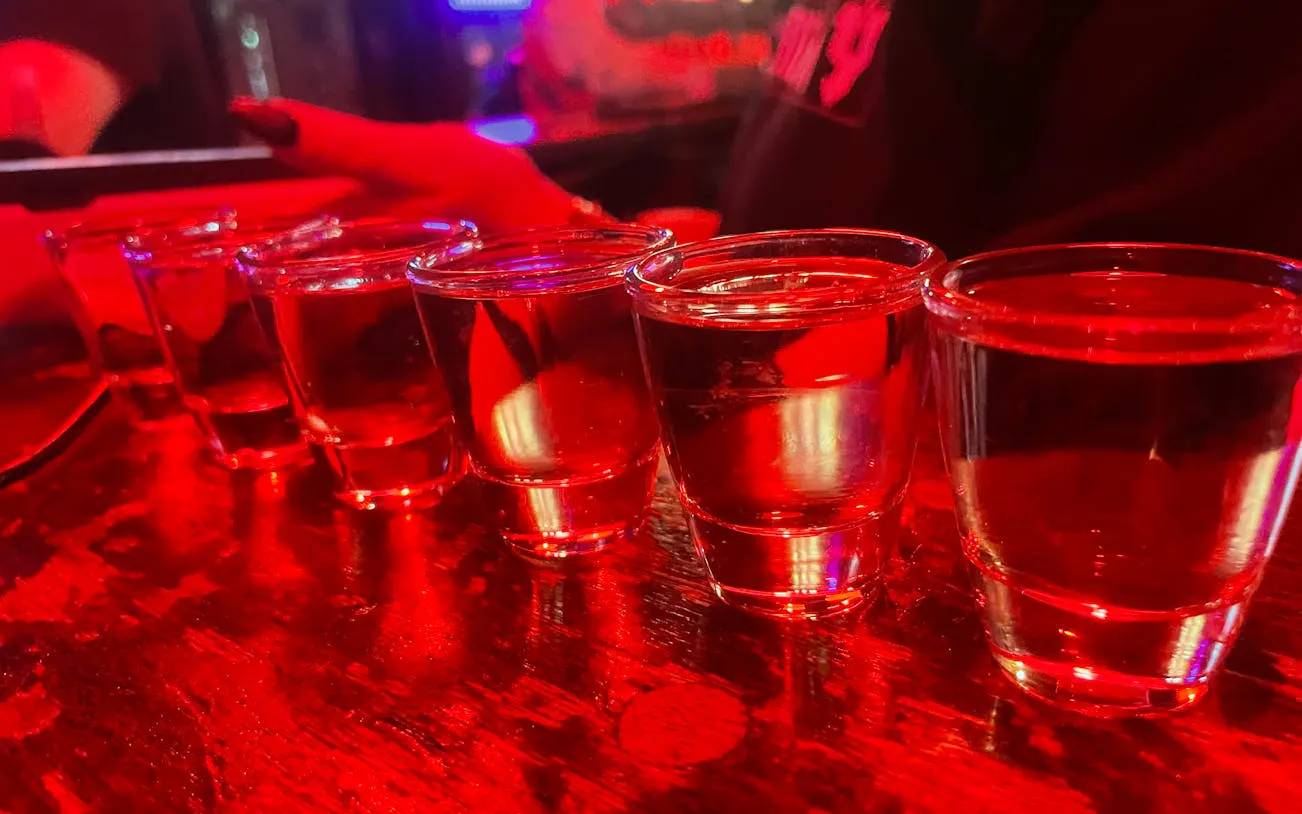 Six shot glasses on a bar counter during Reykjavík private bar crawl.