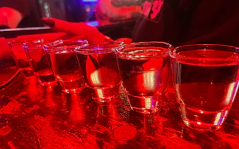 Six shot glasses on a bar counter during Reykjavík private bar crawl.