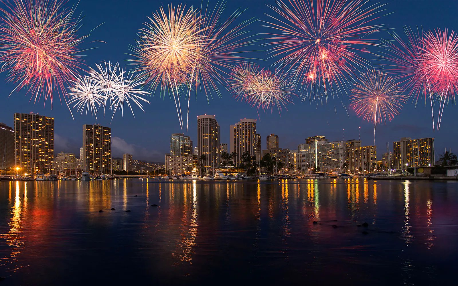 Fireworks over Waikiki skyline during night sail in Honolulu, Hawaii.