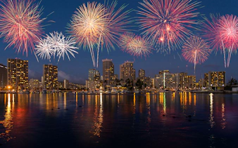 Fireworks over Waikiki skyline during night sail in Honolulu, Hawaii.