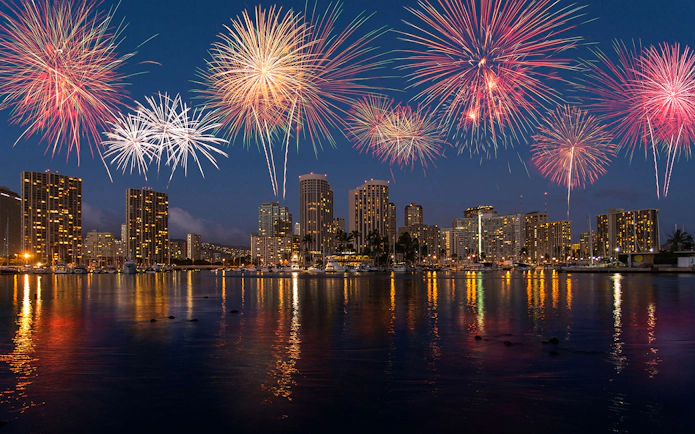 Fireworks over Waikiki skyline during night sail in Honolulu, Hawaii.