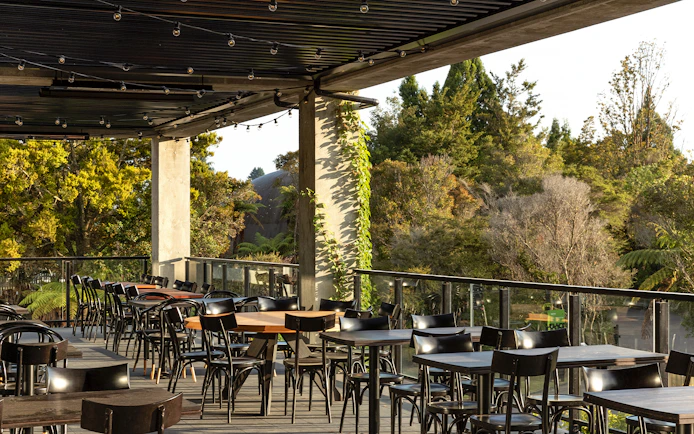 Outdoor dining area at Te Puia with forest view, part of the Te Rā Guided Experience.