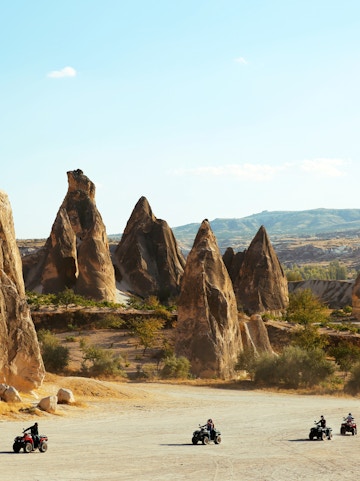 Tourists riding ATVs among rock formations in Cappadocia, Turkey.