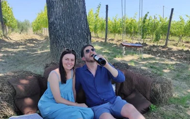 Couple enjoying a picnic in a Tuscan vineyard during a private Tuk Tuk tour.