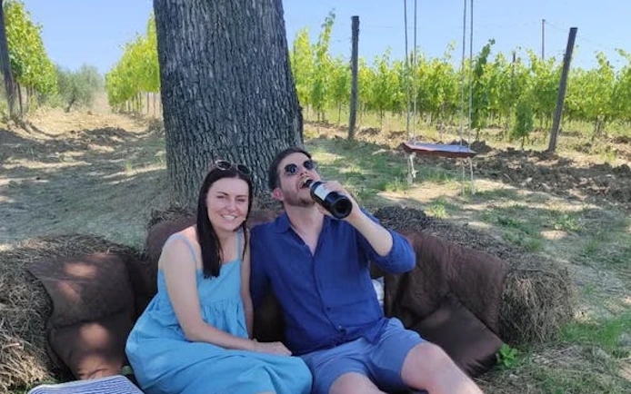 Couple enjoying a picnic in a Tuscan vineyard during a private Tuk Tuk tour.